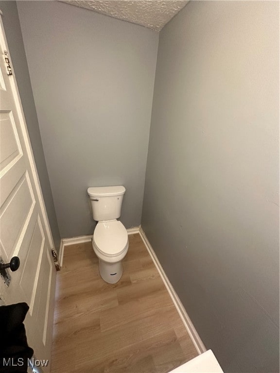 bathroom with wood-type flooring, a textured ceiling, and toilet