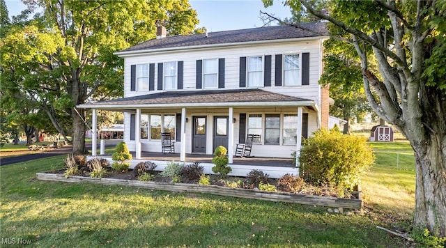 view of front of property with a shed, a front yard, and covered porch