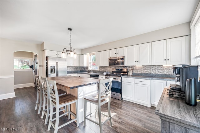 kitchen featuring white cabinets, appliances with stainless steel finishes, dark wood-type flooring, and a healthy amount of sunlight