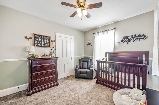 carpeted bedroom with a nursery area, a textured ceiling, and ceiling fan