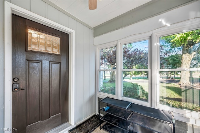 interior space featuring ceiling fan and wood walls