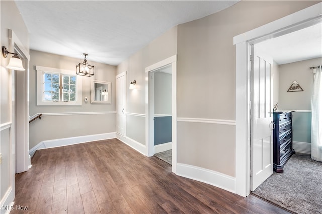 unfurnished dining area featuring a notable chandelier and dark hardwood / wood-style flooring