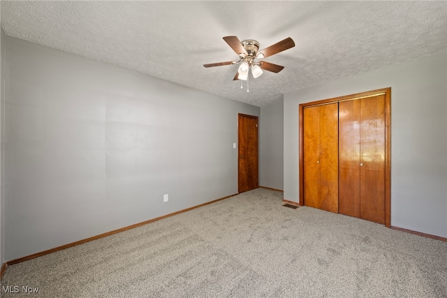 unfurnished bedroom with ceiling fan, a textured ceiling, a closet, and carpet floors