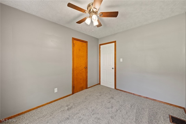 carpeted spare room featuring ceiling fan and a textured ceiling