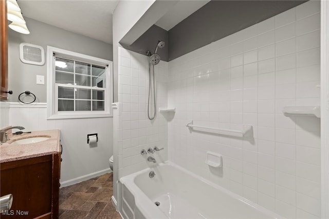 full bathroom with tiled shower / bath, vanity, and toilet