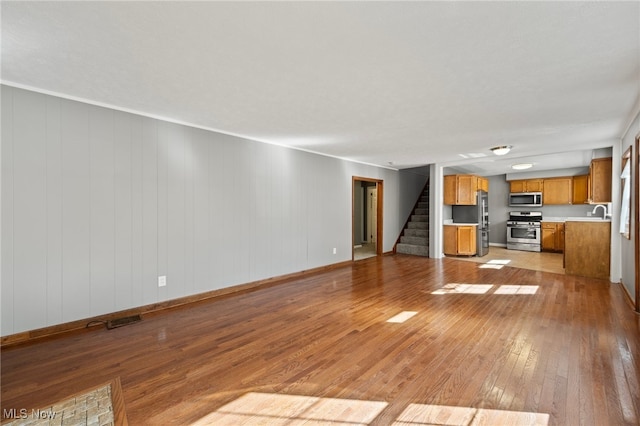 unfurnished living room with light hardwood / wood-style flooring and sink