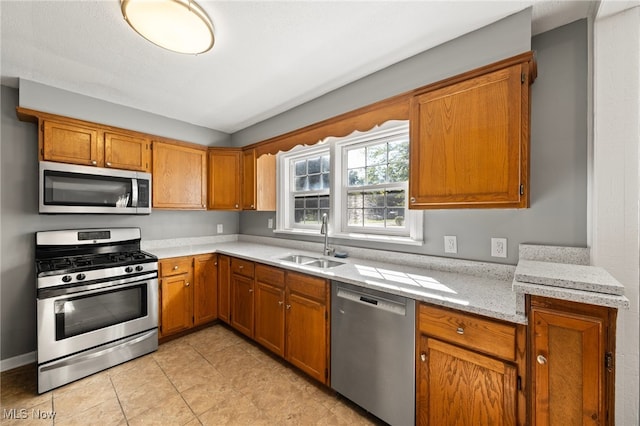 kitchen with light tile patterned flooring, light stone countertops, sink, and stainless steel appliances