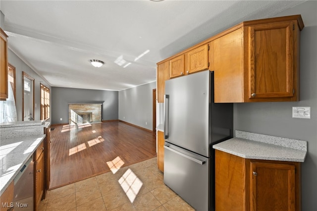 kitchen featuring a brick fireplace, stainless steel appliances, and light hardwood / wood-style flooring