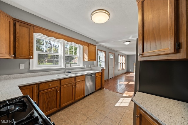 kitchen with black stove, light hardwood / wood-style flooring, sink, dishwasher, and light stone countertops