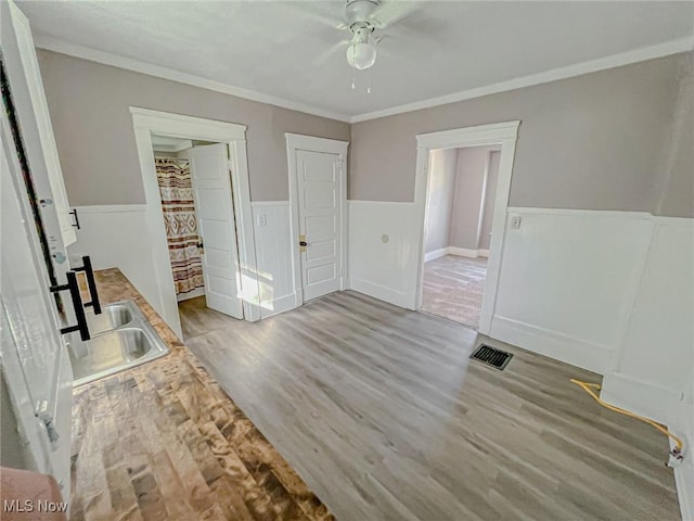 1504 W 19th St, Lorain, OH 44052 - unfurnished bedroom featuring wainscoting, wood finished floors, crown molding, and a ceiling fan