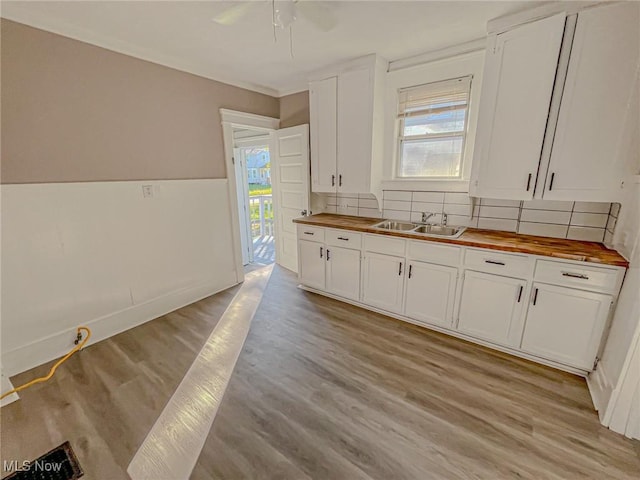 1504 W 19th St, Lorain, OH 44052 - kitchen featuring butcher block countertops, light wood-type flooring, white cabinetry, and tasteful backsplash