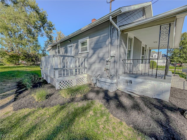 view of side of property featuring a wooden deck and a lawn