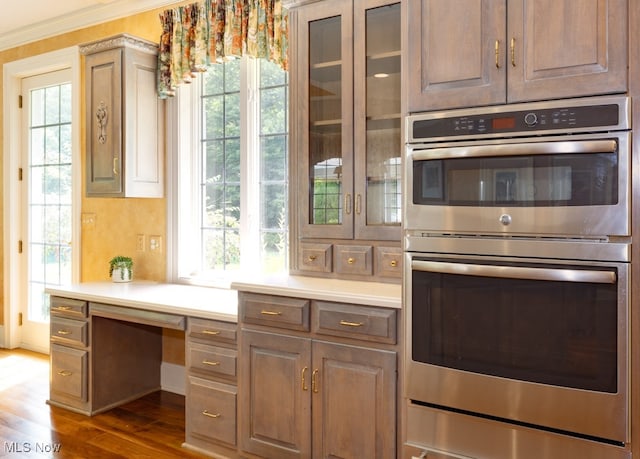 kitchen with stainless steel double oven, built in desk, and plenty of natural light