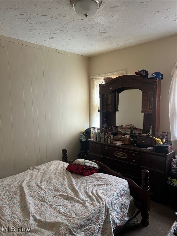 bedroom with wooden walls and carpet floors