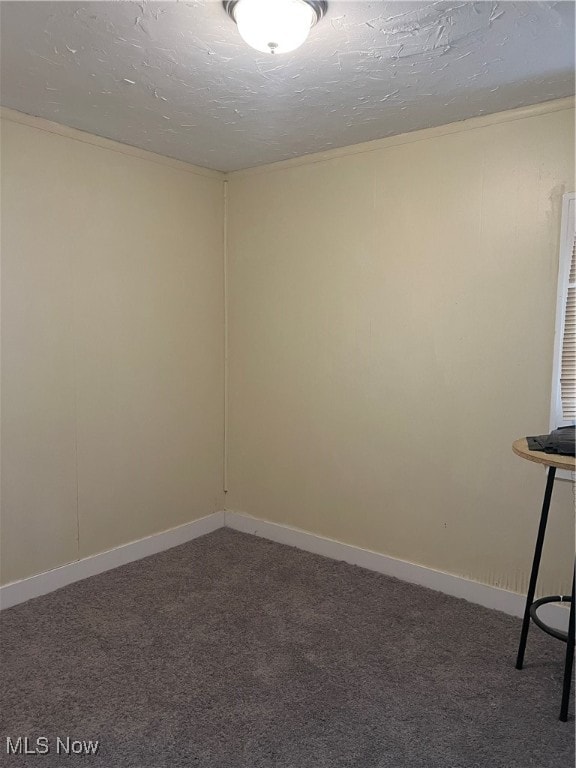 unfurnished room featuring dark carpet and a textured ceiling