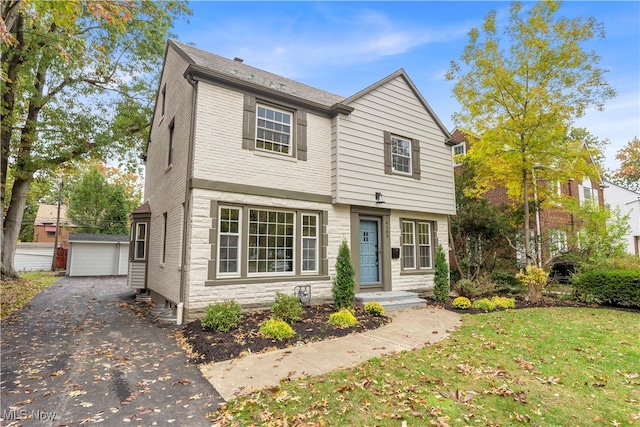 view of front of home featuring a garage, a front lawn, and an outbuilding