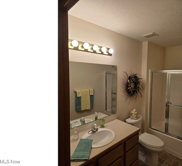 full bathroom featuring vanity, bath / shower combo with glass door, a textured ceiling, and toilet