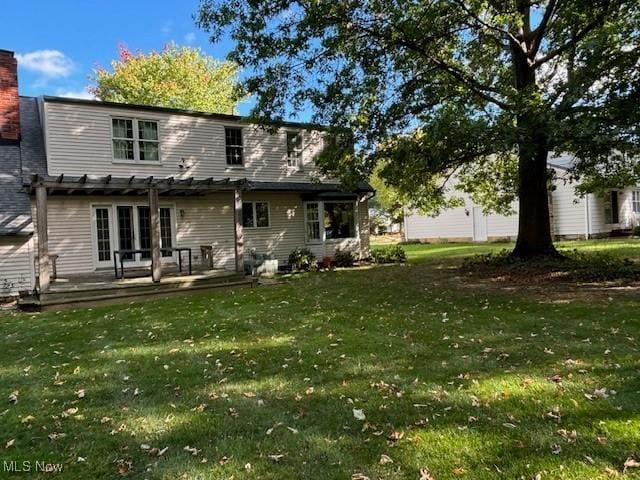 back of house with a lawn, a chimney, a pergola, and a deck