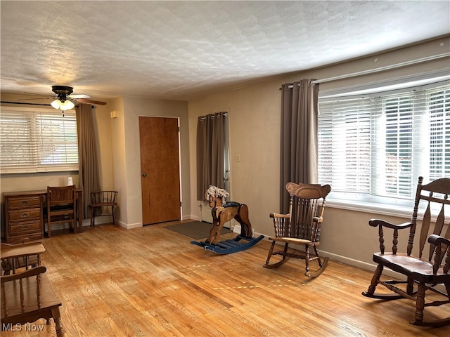 sitting room featuring ceiling fan, a textured ceiling, light hardwood / wood-style flooring, and plenty of natural light