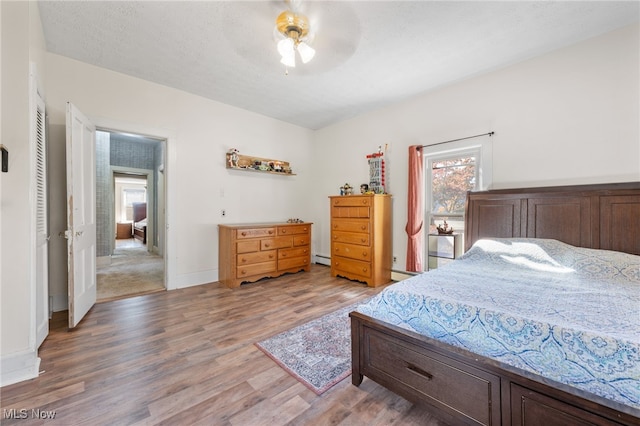 bedroom featuring hardwood / wood-style floors, ceiling fan, and baseboard heating