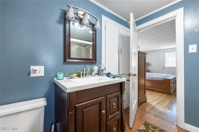 bathroom with hardwood / wood-style floors, vanity, crown molding, toilet, and a textured ceiling