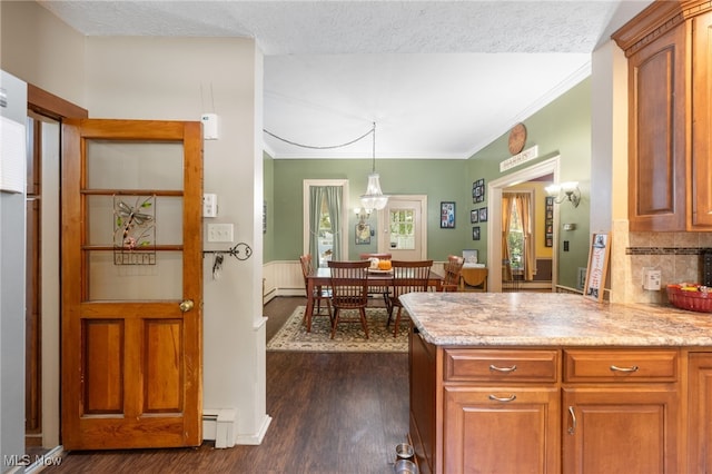 kitchen with backsplash, a textured ceiling, baseboard heating, decorative light fixtures, and dark hardwood / wood-style flooring