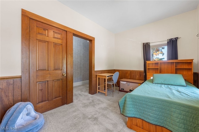 bedroom featuring light colored carpet and wooden walls