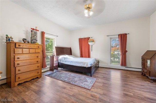 bedroom featuring ceiling fan, dark hardwood / wood-style flooring, a baseboard radiator, and a textured ceiling