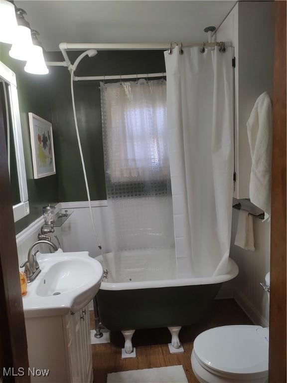 full bathroom featuring hardwood / wood-style flooring, vanity, toilet, and shower / tub combo