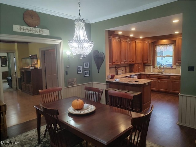 dining space featuring dark hardwood / wood-style floors, ornamental molding, sink, and a chandelier