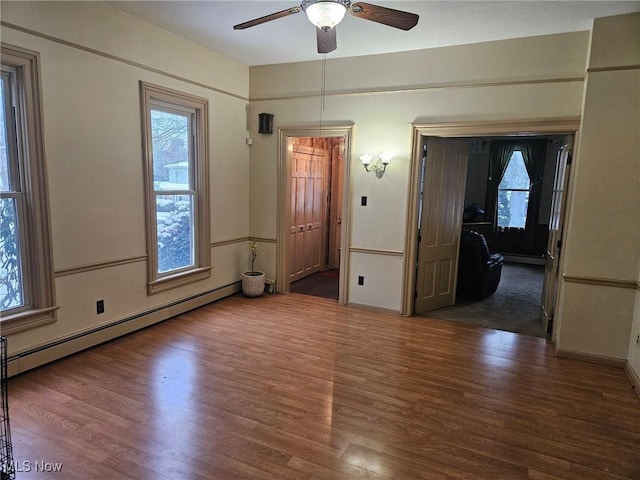 spare room with a baseboard radiator, ceiling fan, and dark hardwood / wood-style floors