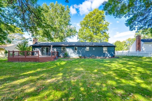 rear view of house with a wooden deck and a yard