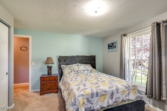 bedroom featuring a closet, light carpet, and a textured ceiling