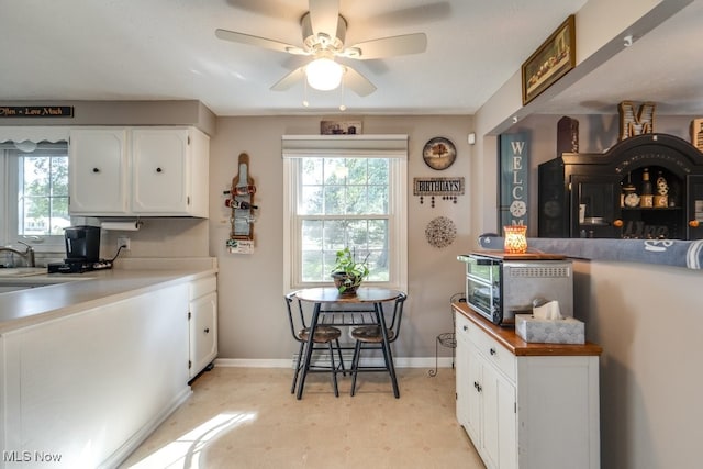 kitchen with ceiling fan and white cabinetry