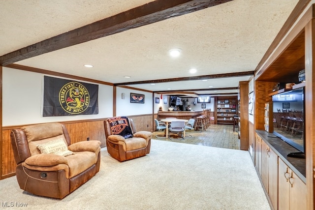 living room with ornamental molding, beam ceiling, indoor bar, carpet, and a textured ceiling