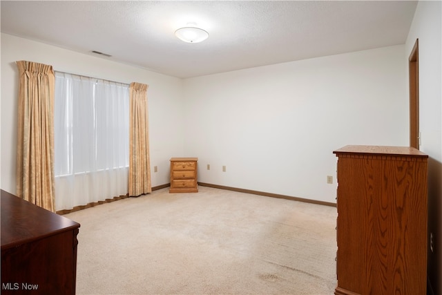 unfurnished room featuring a textured ceiling and light colored carpet