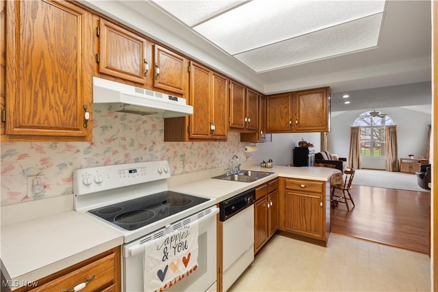 kitchen featuring kitchen peninsula, sink, white appliances, and light wood-type flooring