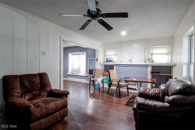 living room with a textured ceiling, ceiling fan, ornamental molding, and dark hardwood / wood-style flooring