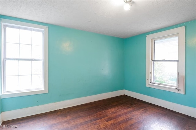 empty room featuring dark hardwood / wood-style floors and a textured ceiling