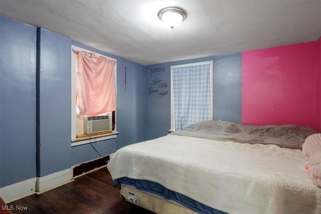 bedroom with a textured ceiling, cooling unit, and dark hardwood / wood-style flooring