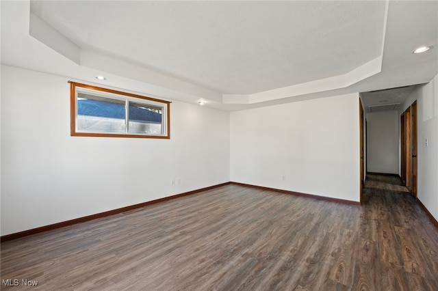 unfurnished room with a tray ceiling and dark hardwood / wood-style flooring