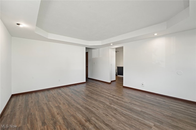 empty room featuring dark wood-type flooring and a raised ceiling