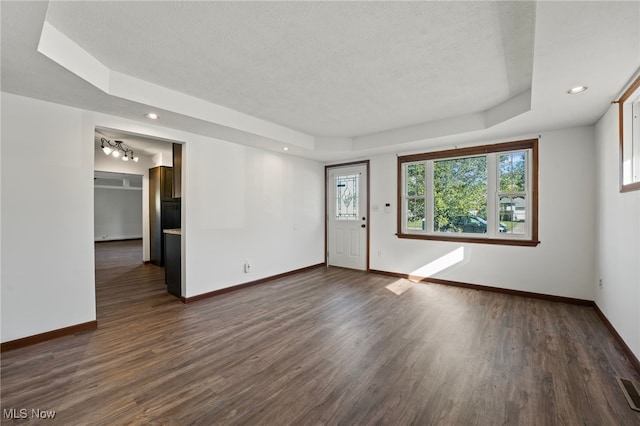 unfurnished room with a wealth of natural light, dark wood-type flooring, a tray ceiling, and a textured ceiling