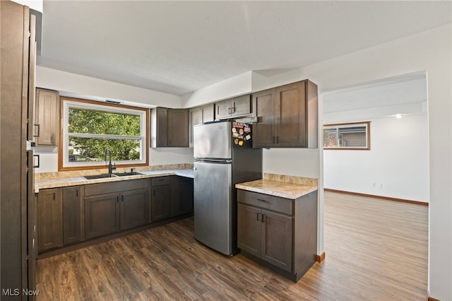 kitchen featuring dark hardwood / wood-style floors, stainless steel fridge, sink, dark brown cabinetry, and a textured ceiling