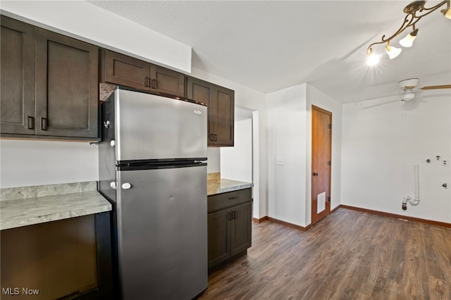 kitchen featuring stainless steel fridge, dark brown cabinets, ceiling fan, dark hardwood / wood-style flooring, and a textured ceiling