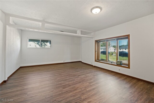 spare room with a textured ceiling and dark hardwood / wood-style flooring