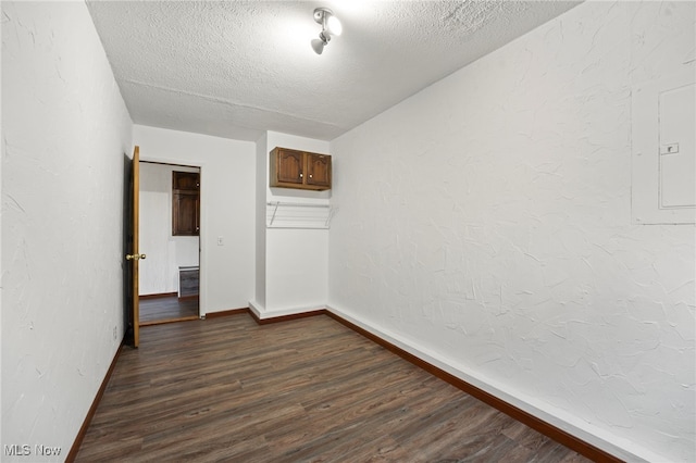 spare room with a textured ceiling and dark hardwood / wood-style floors