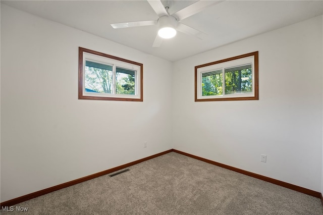 empty room featuring ceiling fan, carpet floors, and plenty of natural light