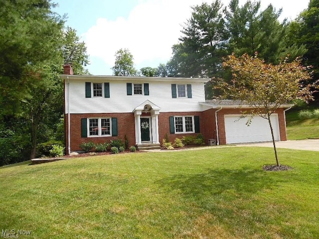 120 Woodcrest Dr, Marietta, OH 45750 - view of front of home with a chimney, brick siding, a garage, concrete driveway, and a front lawn