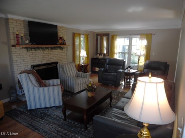 living room with a brick fireplace, hardwood / wood-style flooring, and ornamental molding